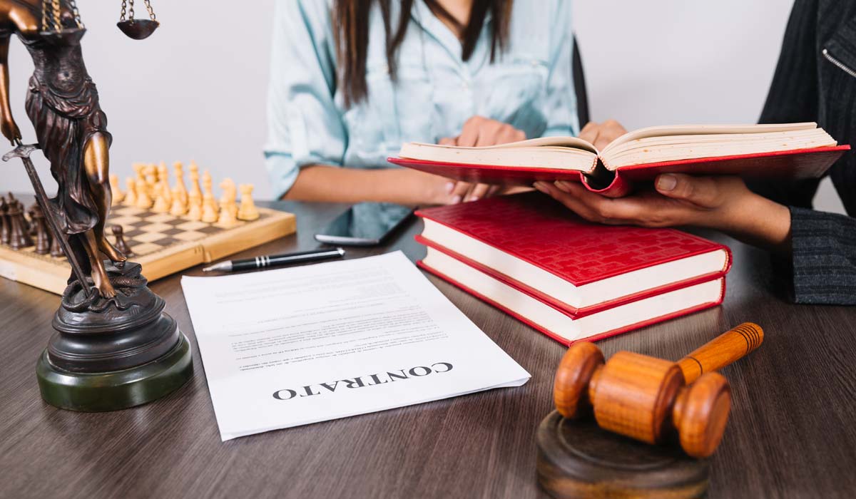 Contrato sobre a mesa ao lado de livros jurídicos e uma estátua da Justiça